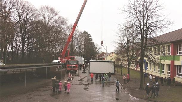 Millimeter-Arbeit vor der Grundschule in Neuenwalde. Ein Kran lässt herunter, was die beengte Klassenraumsituation lindern soll.