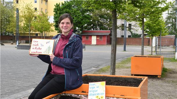 Miriam Gieseking, Leiterin der Quartiersmeisterei Lehe, präsentiert zwei der Schilder, die die Pflanzkästen auf dem Leher Pausenhof vor Vandalismus schützen sollen.