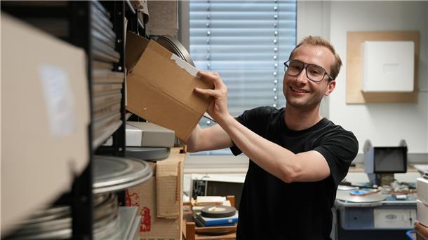 Ein Mann nimmt im Landesfilmarchiv Bremen eine Box mit Filmen aus dem Regal.