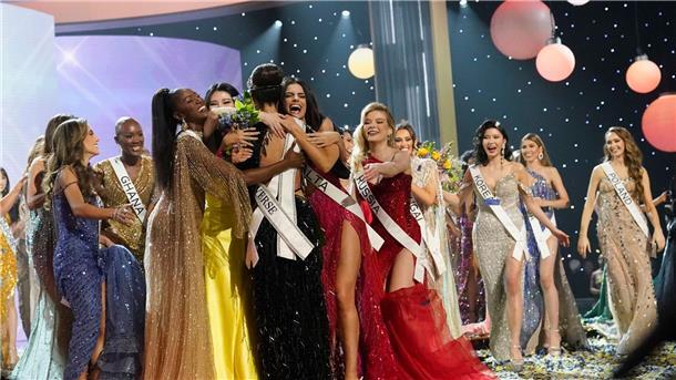 Miss USA R’Bonney Gabriel, mit dem Rücken zur Kamera, wird von Teilnehmerinnen umarmt.