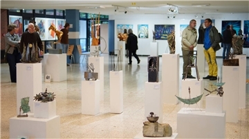 Besucherinnen und Besucher betrachten Skulpturen auf weißen Sockeln in einem hellen Ausstellungsraum der Arche-Ausstellung in der Oberschule Beverstedt.