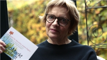 Eine Frau hält eine Karte mit der Aufschrift  "Regiomarkt" in der Hand.