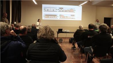 Knappe Entscheidung: Kassebruch bekommt Feuerwehrhaus mit Spitzdach Bürgerinnen und Bürger sitzen in einem Versammlungsraum und verfolgen eine Präsentation zu Entwürfen des neuen Feuerwehrhauses in Kassebruch, die per Beamer an die Wand projiziert werden.