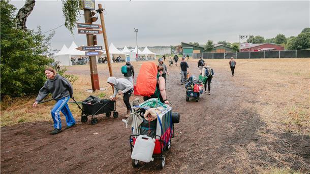 Menschen auf matschigem Feld mit Bollerwagen