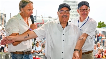 Mit über 60 zum ersten Tattoo: Bei der Eröffnung der Maritimen Tage erhielten Oberbürgermeister Melf Grantz (Mitte) und Stadtverordnetenvorsteher Torsten von Haaren (rechts) ein Klebe-Tattoo mit dem Sail-Schriftzug und Segeln. Ansgar Langhorst von Radio Bremen moderierte das Ganze.