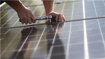 Mitarbeiter einer Firma montieren Photovoltaikmodule auf dem Dach eines Wohnhauses.