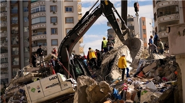 Mitglieder eines Rettungsteams suchen nach Menschen in einem zerstörten Gebäude in Adana.