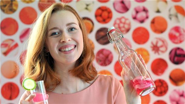 Model Christin hält auf der  Internationalen Süßwarenmesse ein Glas Wodka in der Hand, das mit Sweet Shots-Bonbonmasse versetzt wurde.
