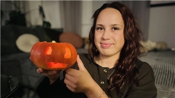 Eine Frau hält eine Kürbislaterne. 