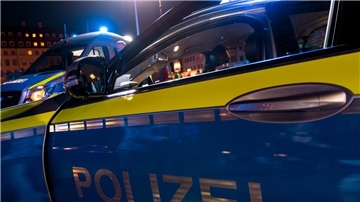Polizeiautos mit offener Tür stehen an einem Einsatzort.