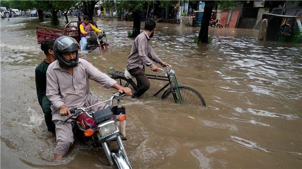 Motorradfahrer auf einer überschwemmten Straße im pakistanischen Lahore.