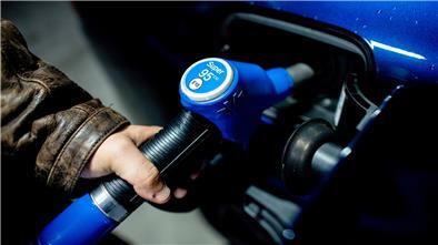 Ein Mann steckt kurz nach Mitternacht die Zapfpistole aus der Tanksäule an einer Tankstelle in sein Fahrzeug, um es mit Super E10 zum Preis von 1,799 Euro je Liter zu betanken.