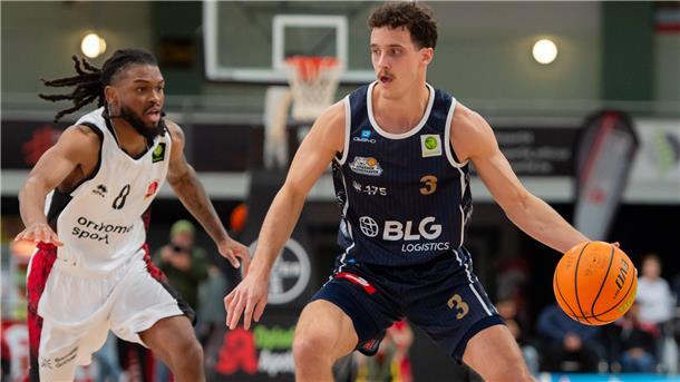 Ein Basketballer ist mit dem Ball auf dem Weg zum Korb.