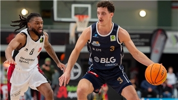 Ein Basketballer ist mit dem Ball auf dem Weg zum Korb.