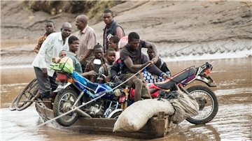 Nach dem Zyklon transportieren Männer in Malawi ihre geretteten Habseligkeiten mit einem Holzboot.