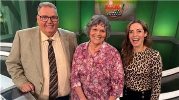 Ein Mann und zwei Frauen stehen in einem Fernsehstudio.