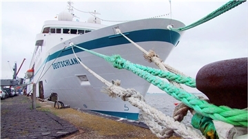 Das Kreuzfahrtschiff „Deutschland“ liegt mit fest verzurrten Tauen an der Columbuskaje in Bremerhaven. Der Schiffsname ist am Bug deutlich zu erkennen.