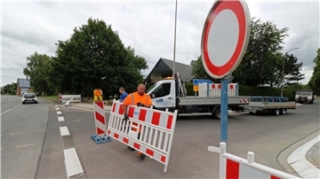 Bauarbeiter räumen eine Straßensperrung von der Fahrbahn