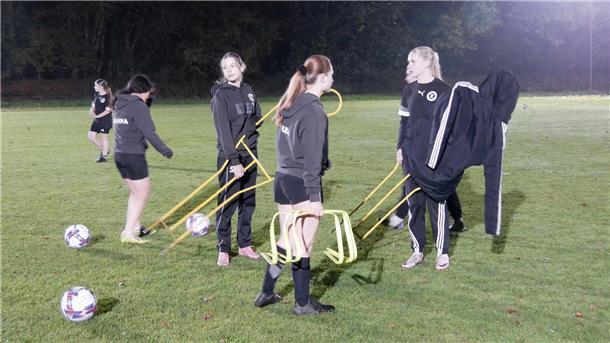 Mädchen in schwarzen Trikots halten Trainingsgeräte in den Händen.