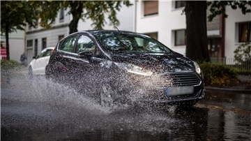 Nach starken Regenfällen am Dienstagmorgen fährt ein Auto durch eine große Pfütze in Duisburg.