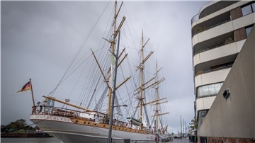 Segelschiff vor Haus.