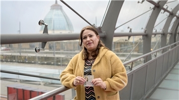 Frau mit einem Ausweis auf einer Brücke