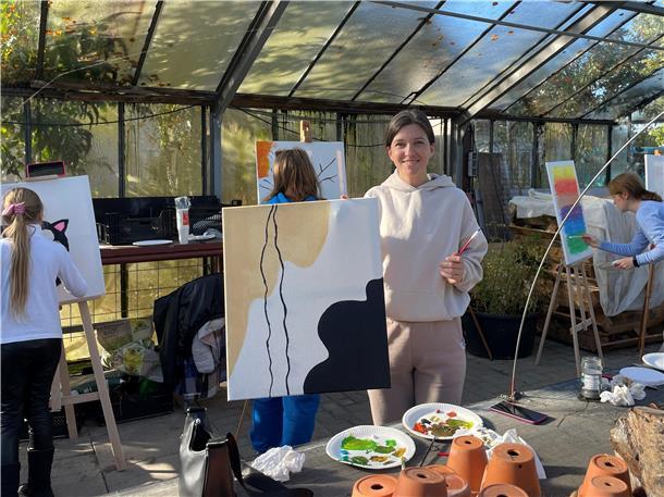 Mehrere Frauen an Staffeleien in einem Gewächshaus