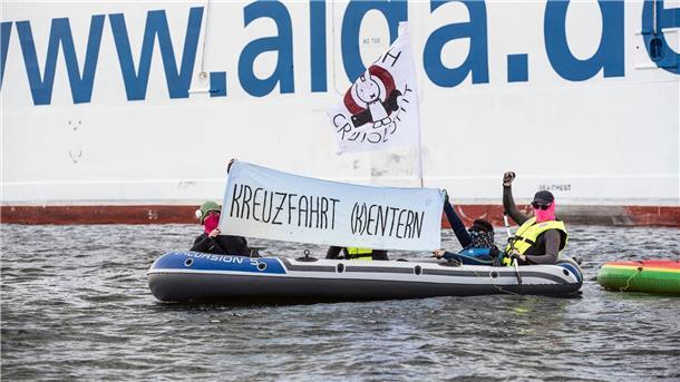 Kreuzfahrtschiff startet nach Klima-Blockade mit Verspätung Neben der „Aida Diva“ halten Klimaaktivisten ein Transparent mit der Aufschrift „Kreuzfahrt (K)entern“.