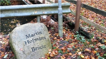 Neben der Mehde-Brücke auf der Schießstandseite liegt der Feldstein, der die Brücke als Martin Hofmann-Brücke ausweist.
