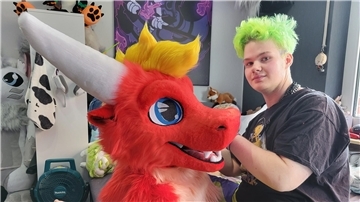 Ein junger Mann näht an einem knallroten Drachen-Kopf