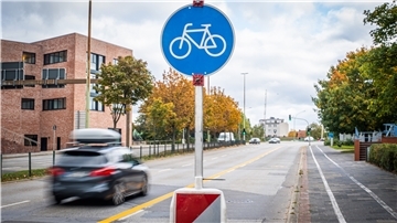 Neue Verkehrszeichen weisen auf Rad- und Fußweg entlang der Kennedybrücke auf die geänderte Regelung hin. Die weißen Linien sind schwer zu entfernen und sollen zunächst mit Kreuzen als ungültig markiert werden.