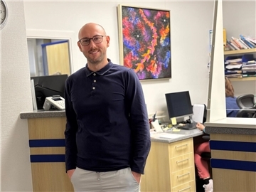 Mediziner Benjamin Weber-Garst steht am Empfang der Landarztpraxis und blickt in die Kamera.