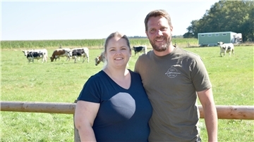 Ein Mann und eine Frau vor einer Wiese mit Rindern.