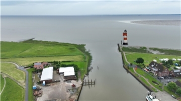 Luftbild eines Hafens an der Nordsee mit einem Leuchtturm an der Hafenausfahrt
