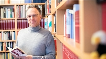 Sebastian Loskant mit Gedichtband von Robert Gernhardt vor Bücherwand