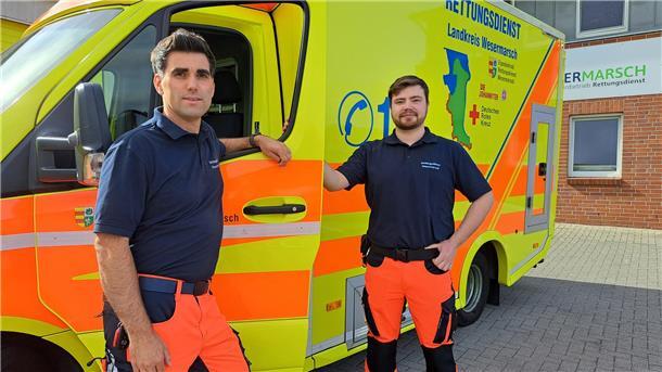 Bild von Notfallsanitäter Dennis Timmermann (l.) und Luca Petarus, Auszubildender zum Notfallsanitäter, vor einem Rettungswagen