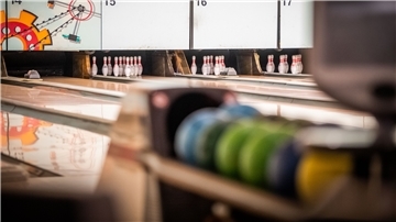 Bowlingkugeln liegen an einer Bowlingbahn.