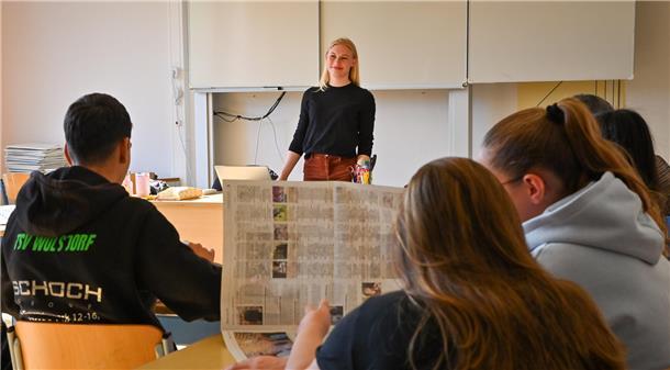 So geht Journalismus: NZ-Reporter im Klassenzimmer zu Medienkompetenz Eine Frau steht in einem Klassenzimmer an einer Tafel, Schüler sitzen im Klassenraum und hören zu.