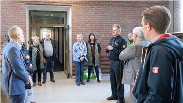 Sechs Männer und fünf Frauen stehen vor einem Polizeirevier und lächeln in die Kamera.