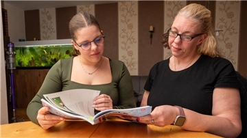 Zwei Frauen sitzen an einem Tisch und blättern in einem Buch