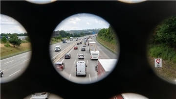 Ein Blick durch ein Geländer einer Autobahnbrücke auf die Fahrbahn.