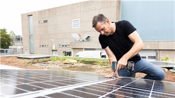 Olaf Lies, damals noch als Wirtschaftsminister, montiert ein Solarmodul auf ein Dach. (Archivbild)