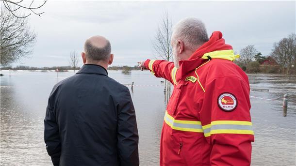 Olaf Scholz (l) steht mit einem Helfer der DLRG an einem überfluteten Gebiet in Verden/Aller.