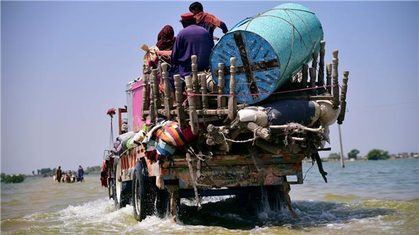 Heißer und extremer: Der Zustand des Klimas im Überblick Opfer von Überschwemmungen durch Monsunregen tragen Habseligkeiten aus ihrem überfluteten Haus in der Provinz Sindh.