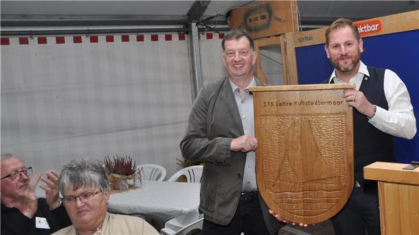 Ortsvorsteher Adrian Stelljes (links) freut sich über ein Geschenk von Gnarrenburgs Gemeindebürgermeister Marc Breitenfeld, der der Ortschaft am Freitagabend ein von Hand gefertigtes, großformatiges Ortschaftswappen überreichte.