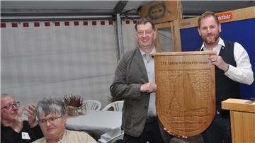 Ortsvorsteher Adrian Stelljes (links) freut über ein Geschenk von Gnarrenburgs Gemeindebürgermeister Marc Breitenfeld, der der Ortschaft am Freitagabend ein von Hand gefertigtes, großformatiges Ortschaftswappen überreichte.