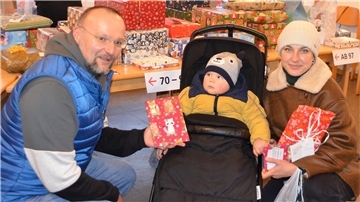 Pastor Dirk Glanert überreicht die Weihnachtsgeschenke für die Kinder an Mama Iryna. Der kleine Anton zeigt noch eine gewisse Skepsis, Iryna jedoch zaubert die Bescherung ein Lächeln ins Gesicht.