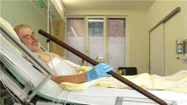 Patient Frank Vaorin liegt im Krankenhausbett und hält die Zaunstange in der Hand, die seinen Körper durchbohrte.