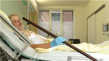Patient Frank Vaorin liegt im Krankenhausbett und hält die Zaunstange in der Hand, die seinen Körper durchbohrte.