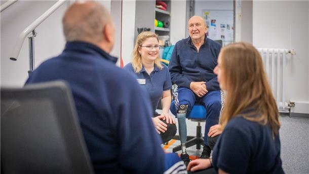 Patient Wolf-Dieter Seifert wird von Pia Henke (links) und Alexandra Lapp physio- und ergotherapeutisch versorgt. Gemeinsam arbeiten sie daran, dass Seifert bald ohne Rollator laufen kann. 